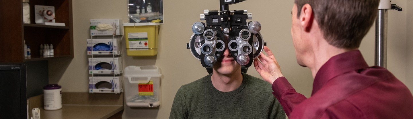 a male optometerist adjusting a phoropter for a male patient during an eye exam spokane eye clinic