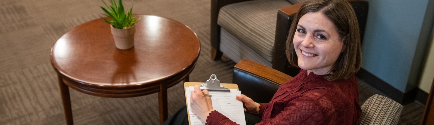 a smiling woman with a patient form on a clipboard spokane eye clinic